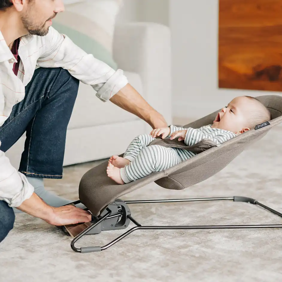 Parent adjusting the bouncer while child is seated
