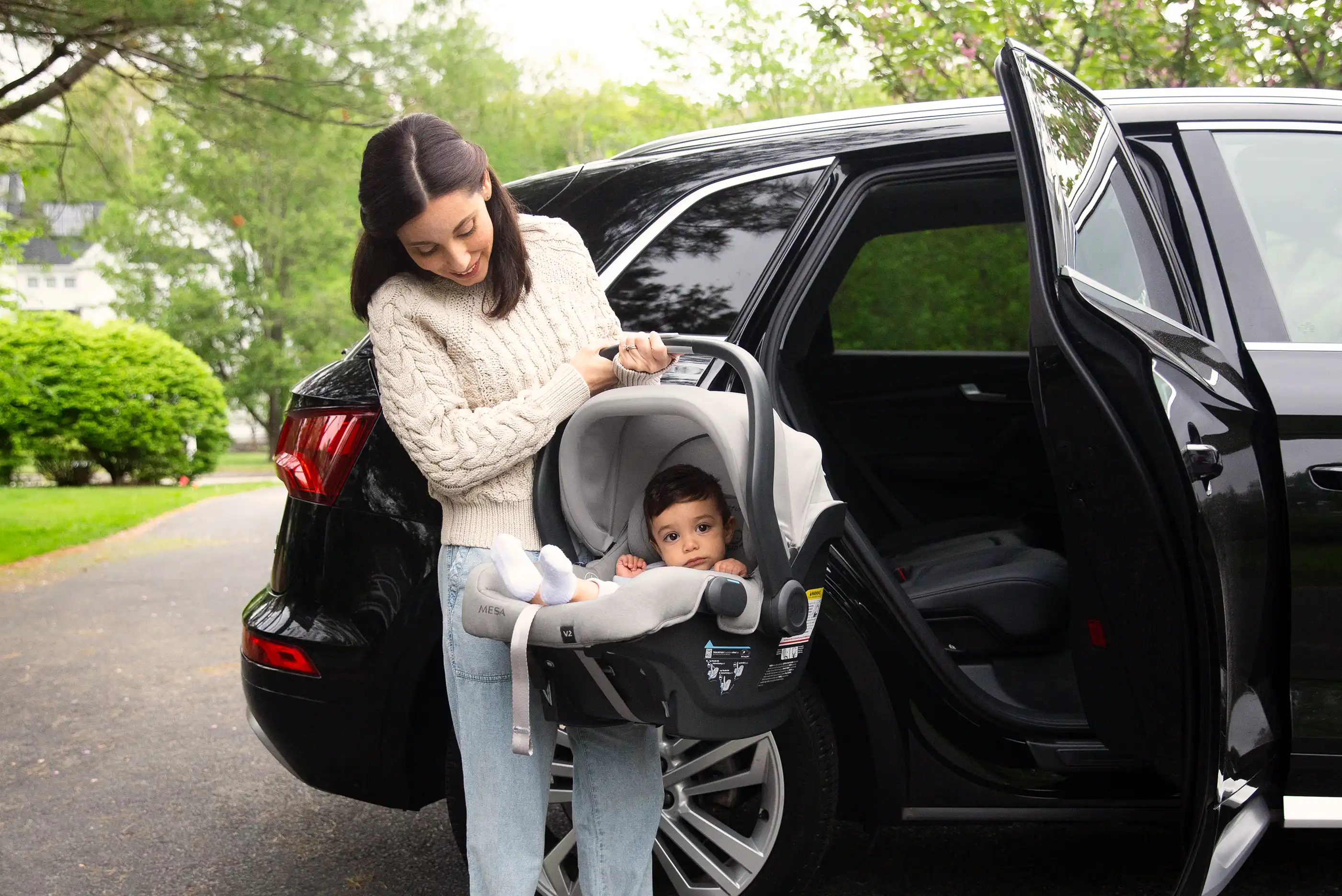 Parent removes child and car seat from back seat of vehicle