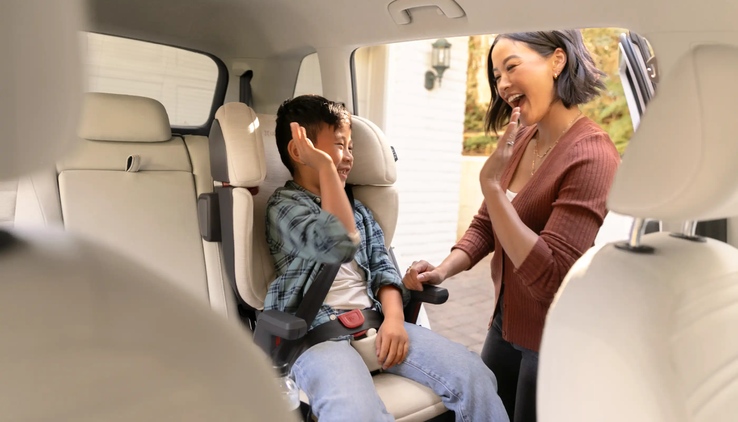 Parent giving child in car seat a high-five while laughing