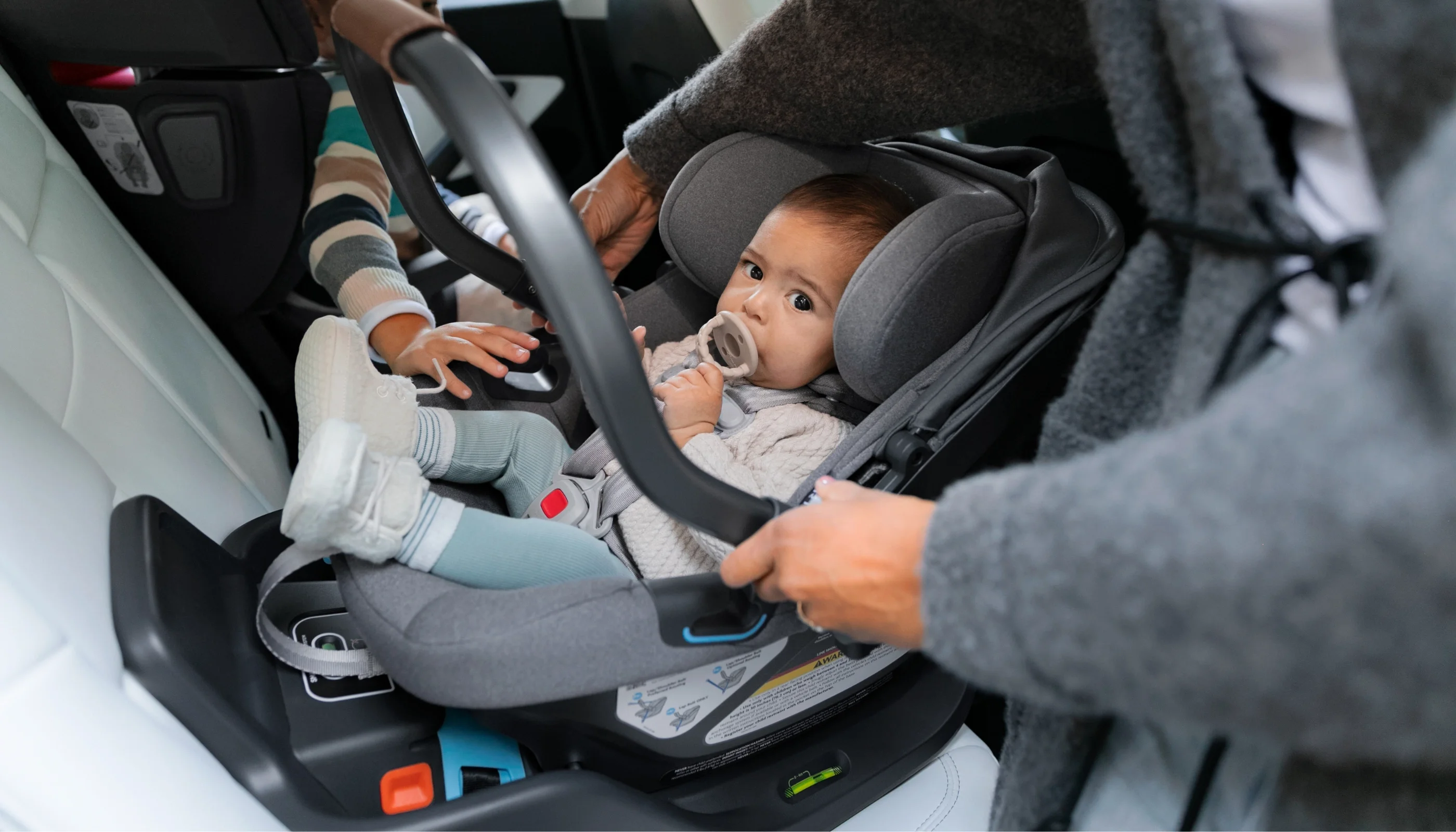 Child securely fastened in their car seat being installed in the car