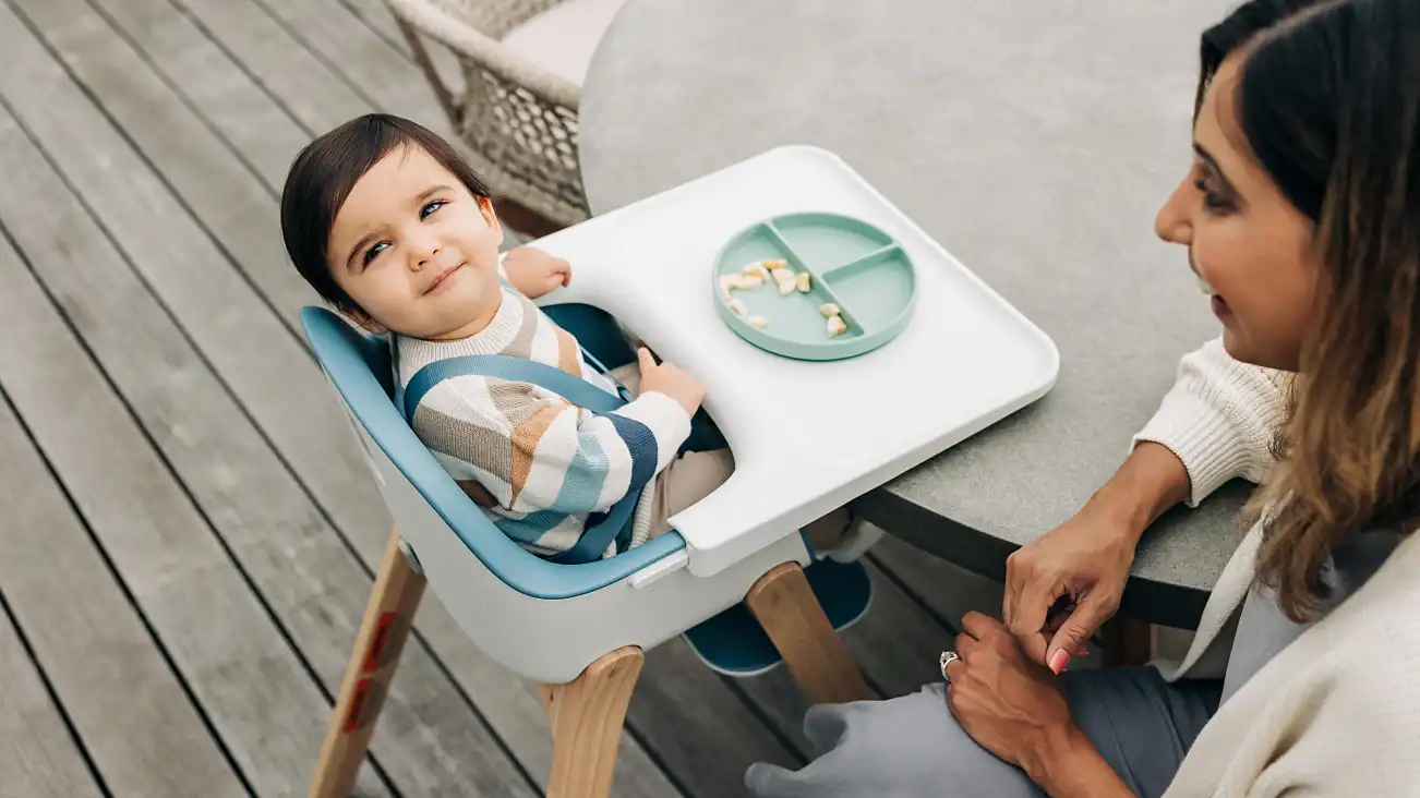 A child sits happily with their plate on the tray